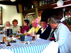 am weiß-blau gedeckten Tisch von vorne: Inge, Das Ehepaar Spangenberg, Adele, Inge