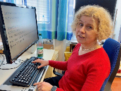 Silvia am Schreibtisch mit Tastatur und Braillezeile