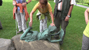 Bronzeskulptur im Kurpark: auf einem Stein liegt bäuchlings ein Mädchen und liest in einem Buch. Margit erkundet die Figur mit den Händen