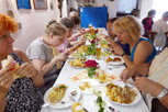 Mittagsessen, in der Mitte Tisch, Teilnehmer sitzen links und rechts