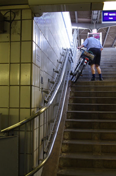 Treppenaufgang zum Bahnsteig, in der Mitte Radfahrer mit seinem Fahrrad