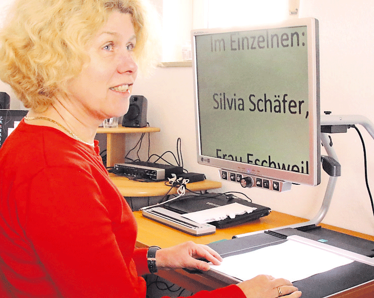 Silvia Schäfer vor der elektronischen Lupe und Braillezeile vor dem Computer
