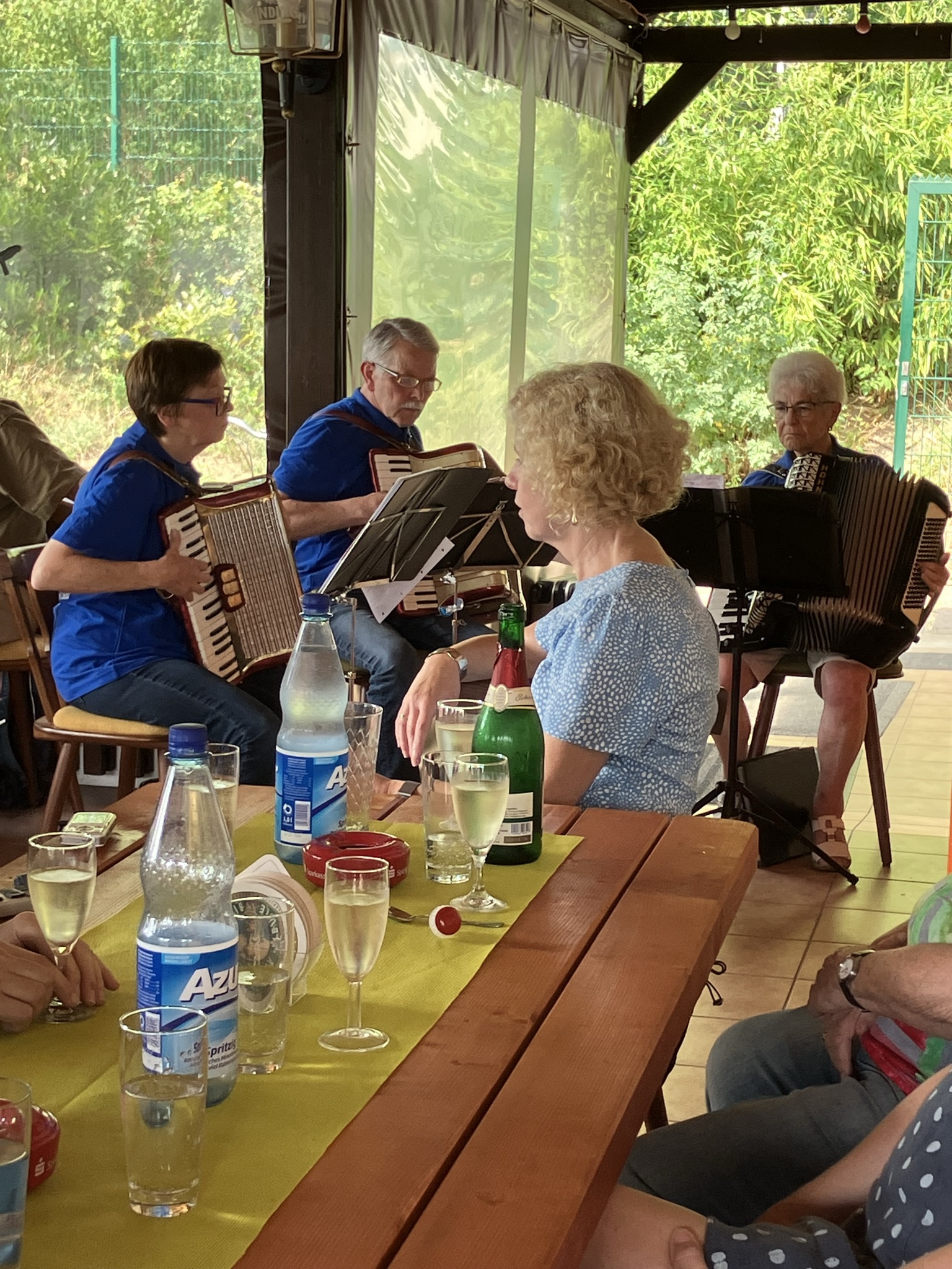 Eine Gruppe von Musikern mit Akkordeons. Auf dem Tisch im Vordergrund stehen Getrnke.