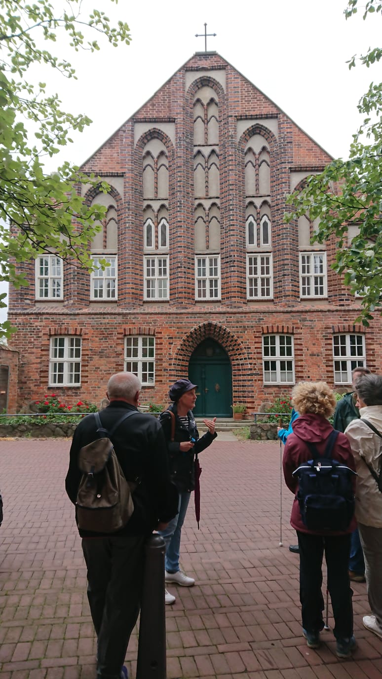 Die Reisegruppe steht mit der Stadfhrerin vor einem alten Gebude. Sie scheint den Anwesenden etwas zu erklren.